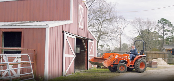 Landowner on a tractor in front of a barn