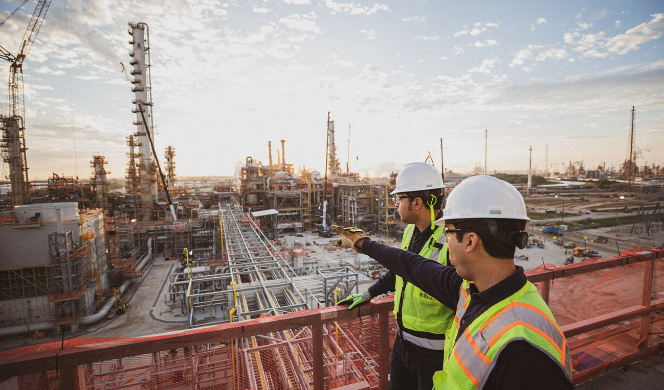 workers at an industrial complex with one pointing